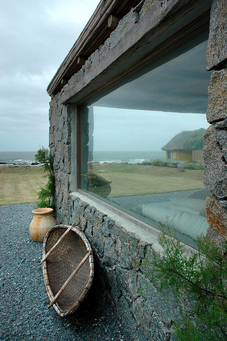 Coastal beach house exterior with exposed stone and large window