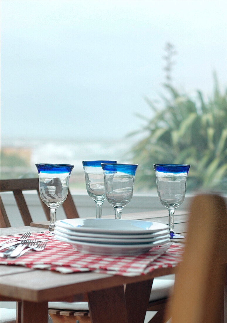 Trinkgläser und Teller auf dem Terrassentisch eines Strandhauses