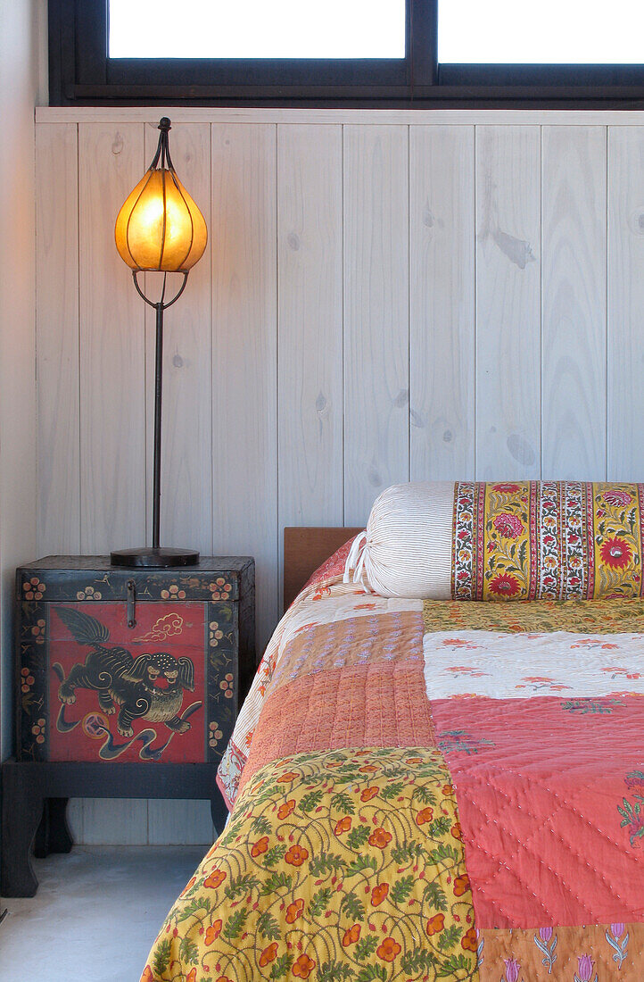 Matching bed linen and exposed stone wall with lit lamp on nightstand