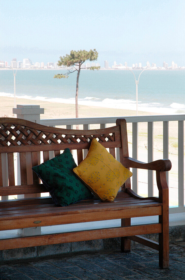 Holzbank mit Kissen auf einem Außenbalkon an der Küste