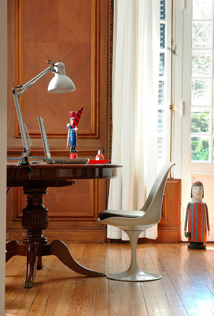 Chair at desk with desk lamp in panelled study