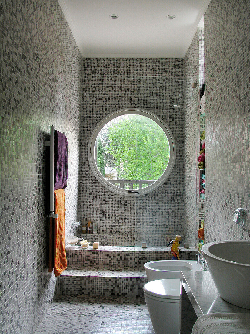 Circular window in grey tiled wet room