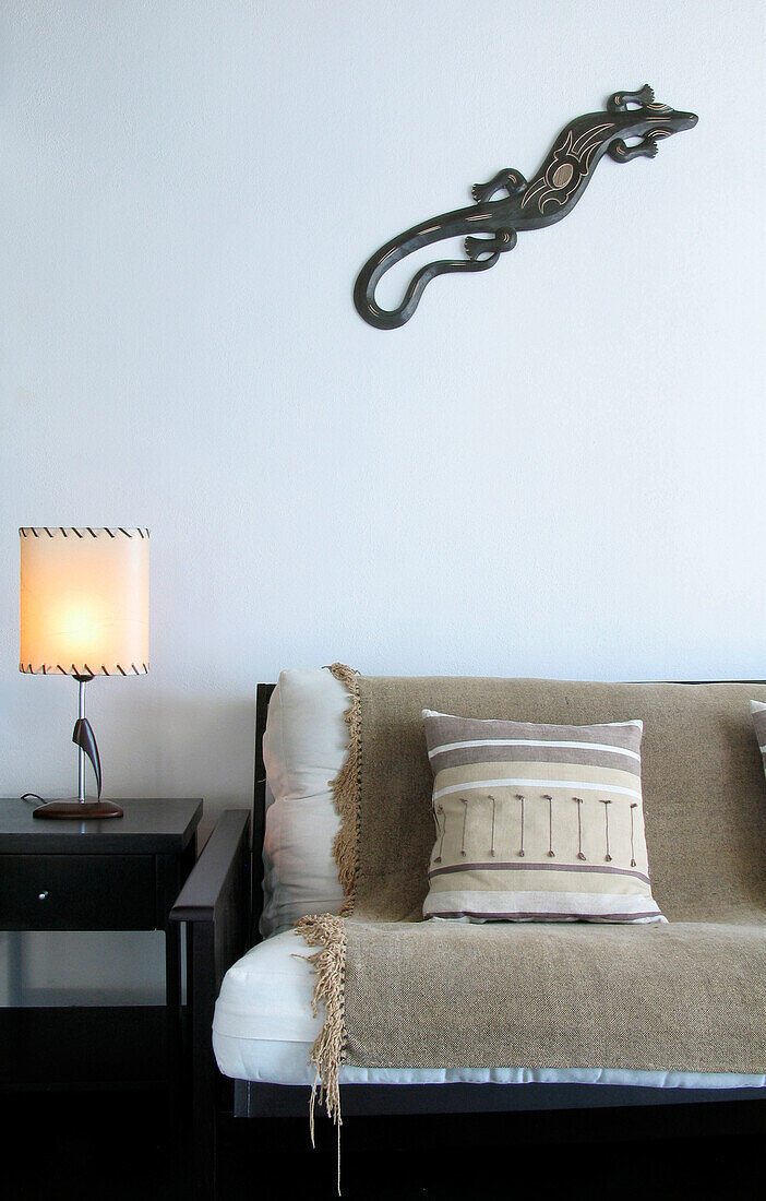 Beigefarbene Decke und Kissen auf Sofa mit Beistelltisch und beleuchteter Lampe