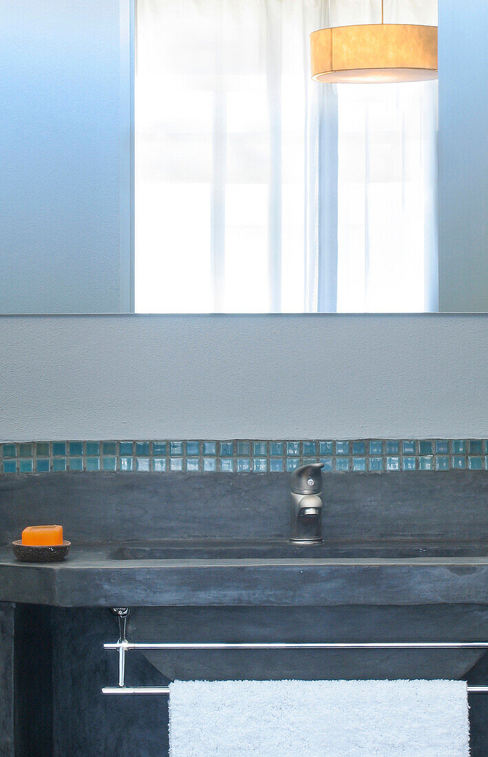Washbasin and towel rail under mirror reflecting light