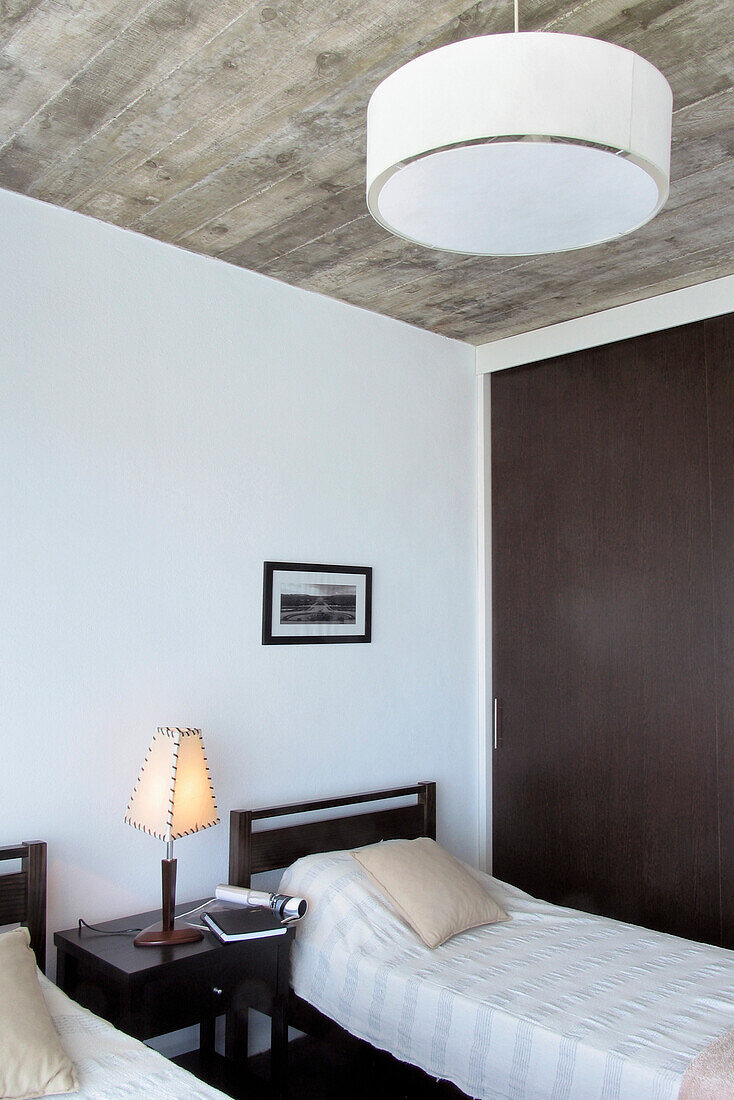Zwei Einzelbetten in einem Zimmer mit einem großen weißen Lampenschirm