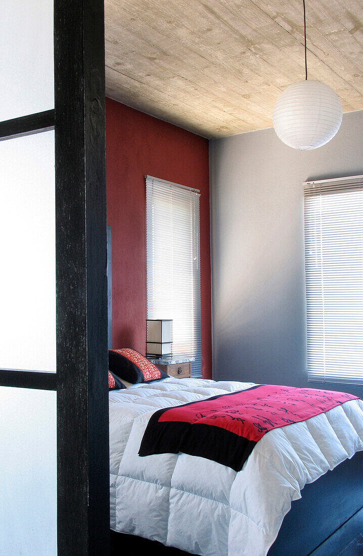 Blick in ein Schlafzimmer mit silbernen und roten Wänden und einer Holzdecke