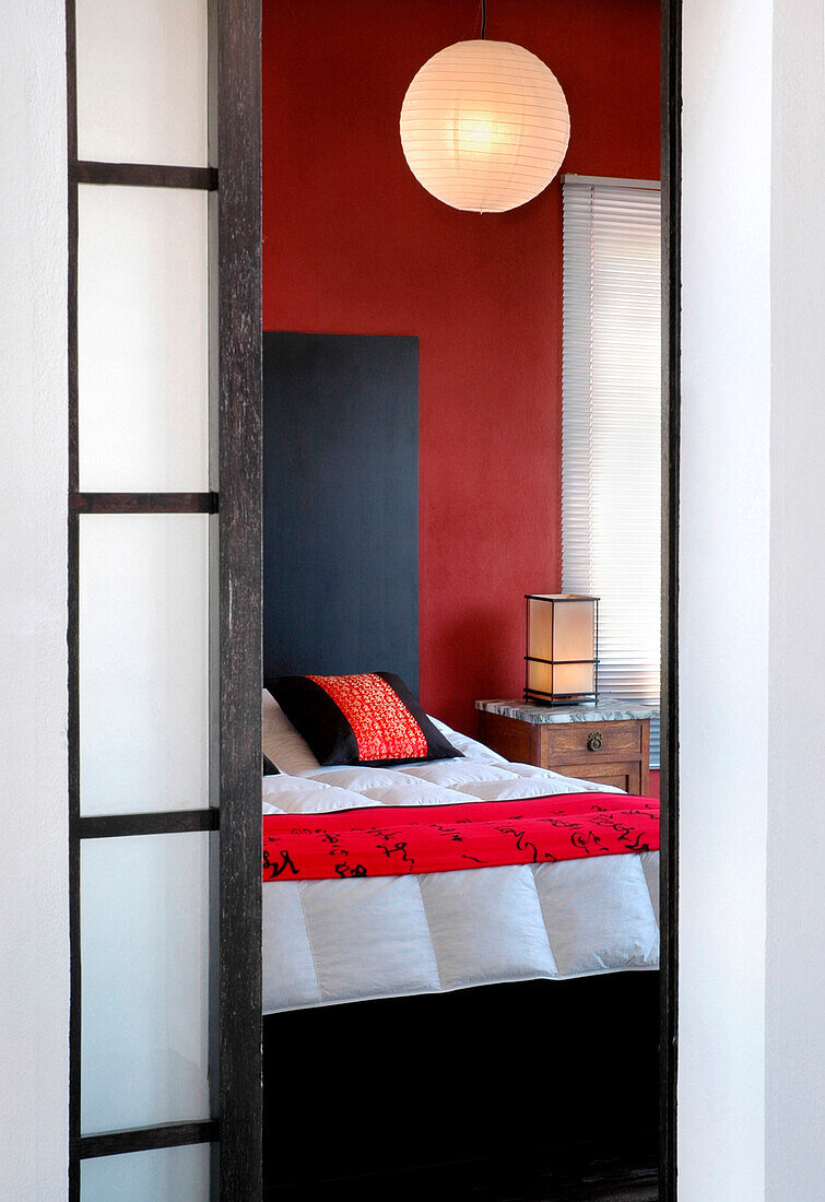Blick durch eine undurchsichtige Schiebetür in ein orientalisches Schlafzimmer mit Pendelleuchte