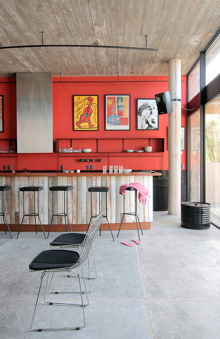 Recycelte Küchentheke mit Lapacho-Platte und gusseisernen Hockern mit schwarzen Ledersitzen Verputzte, rot gestrichene Wände