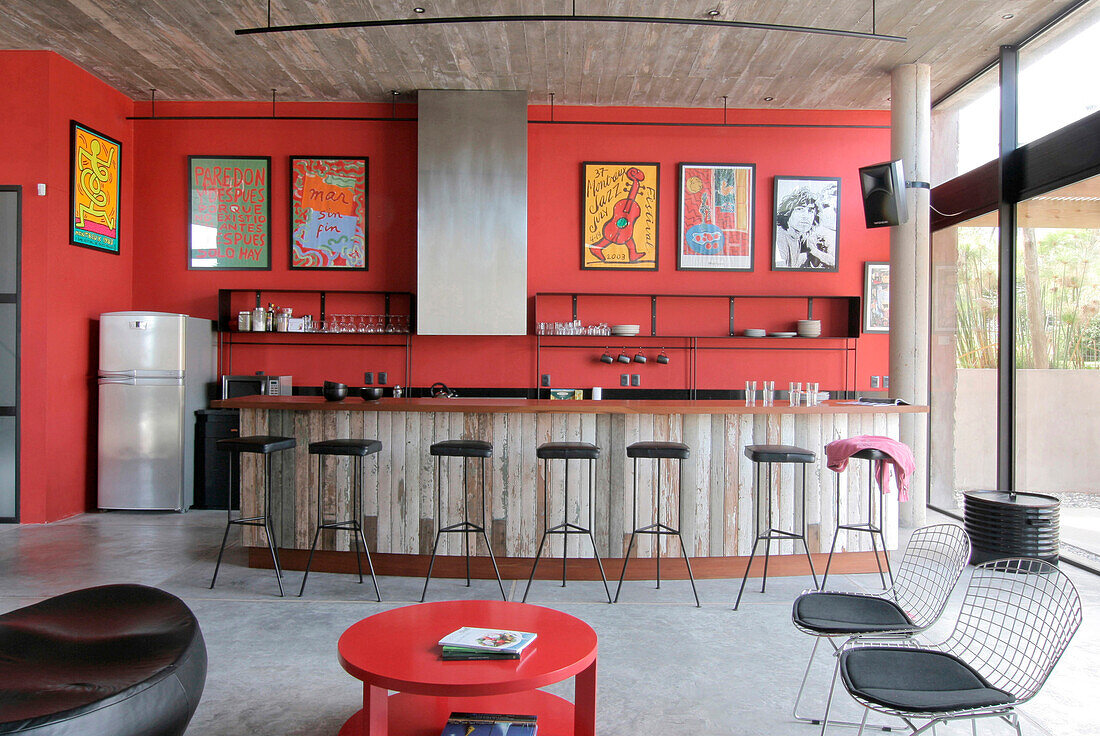 Recycelte Küchentheke mit Lapacho-Platte und gusseisernen Hockern mit schwarzen Ledersitzen Verputzte, rot gestrichene Wände