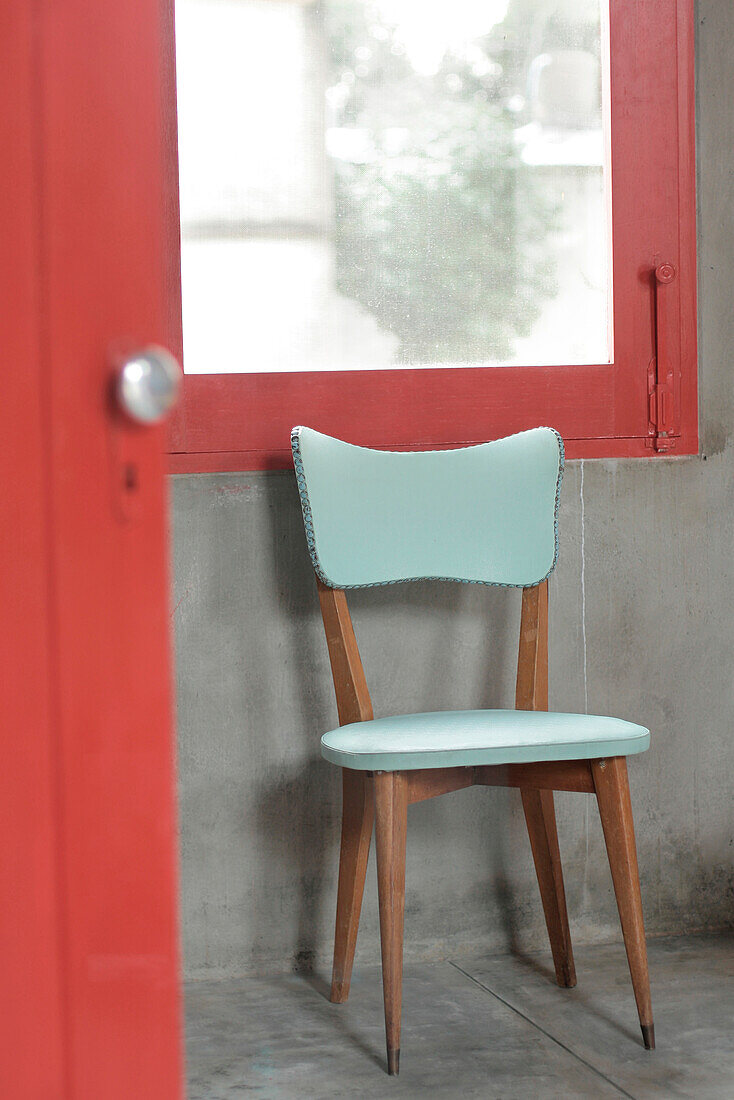 Aquamarinfarbener Stuhl, der bei einer Auktion unter einem roten Fensterrahmen gefunden wurde