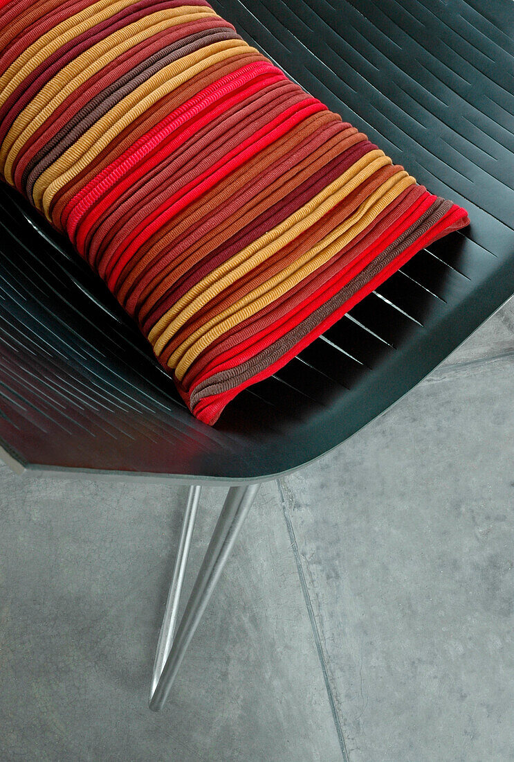 Gestreiftes Kissen auf einem schwarzen Stuhl mit Metallrahmen
