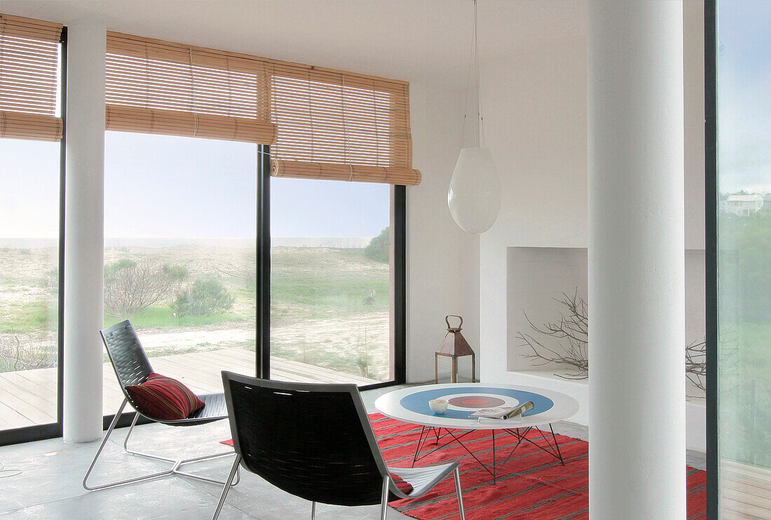 Metal framed chairs in beach house interior with supporting pillars