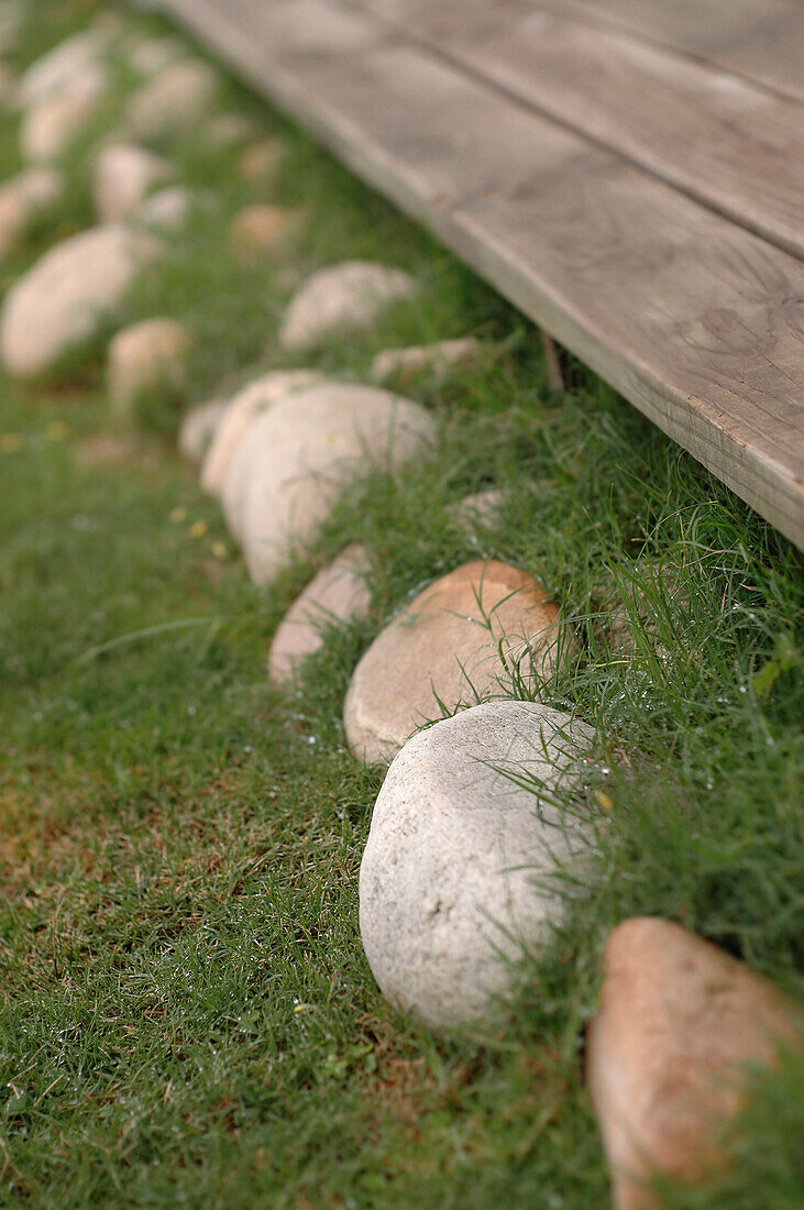 Kieselsteine am Rande des Rasens eines Strandhauses