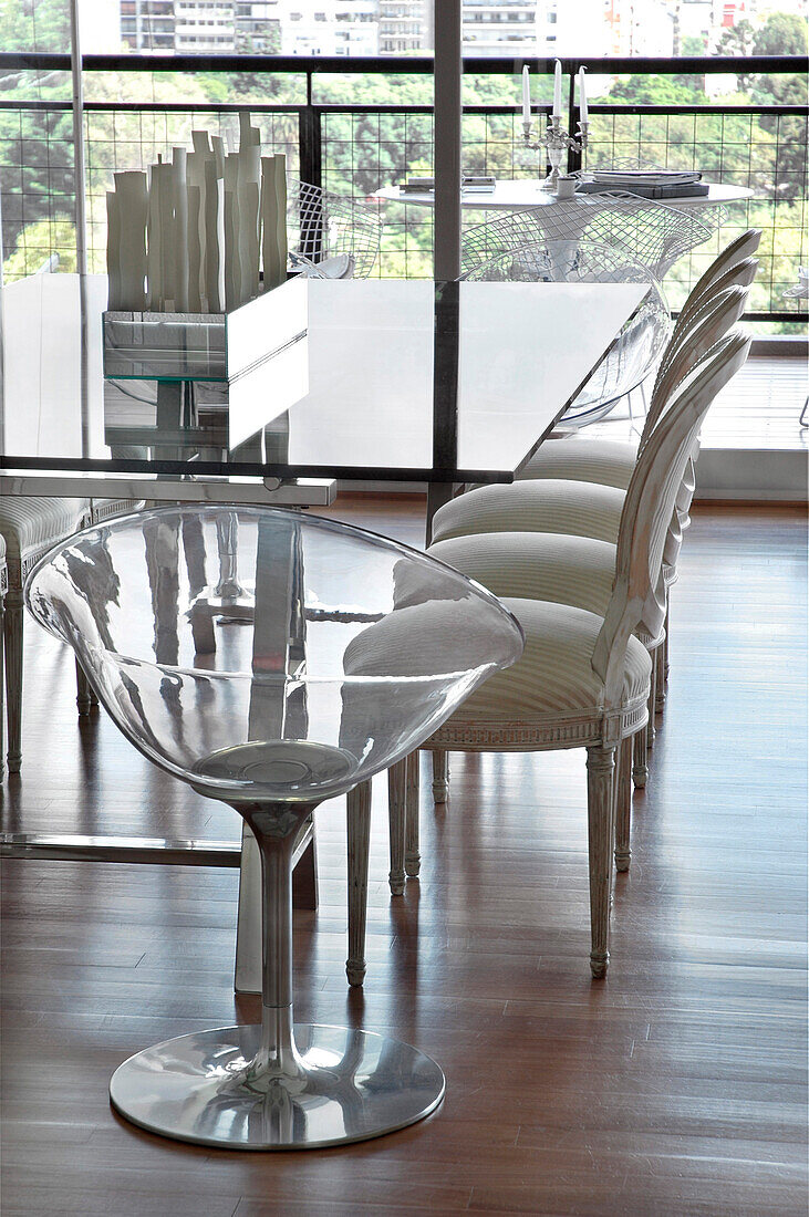 Glass topped dining table with reflective light and chairs on wooden floor
