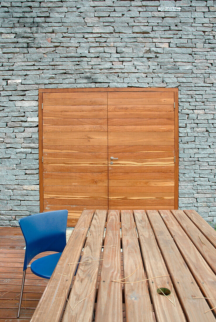 Moderner Essbereich im Außenbereich mit unbearbeiteter Steinwand und Doppeltüren aus Holz