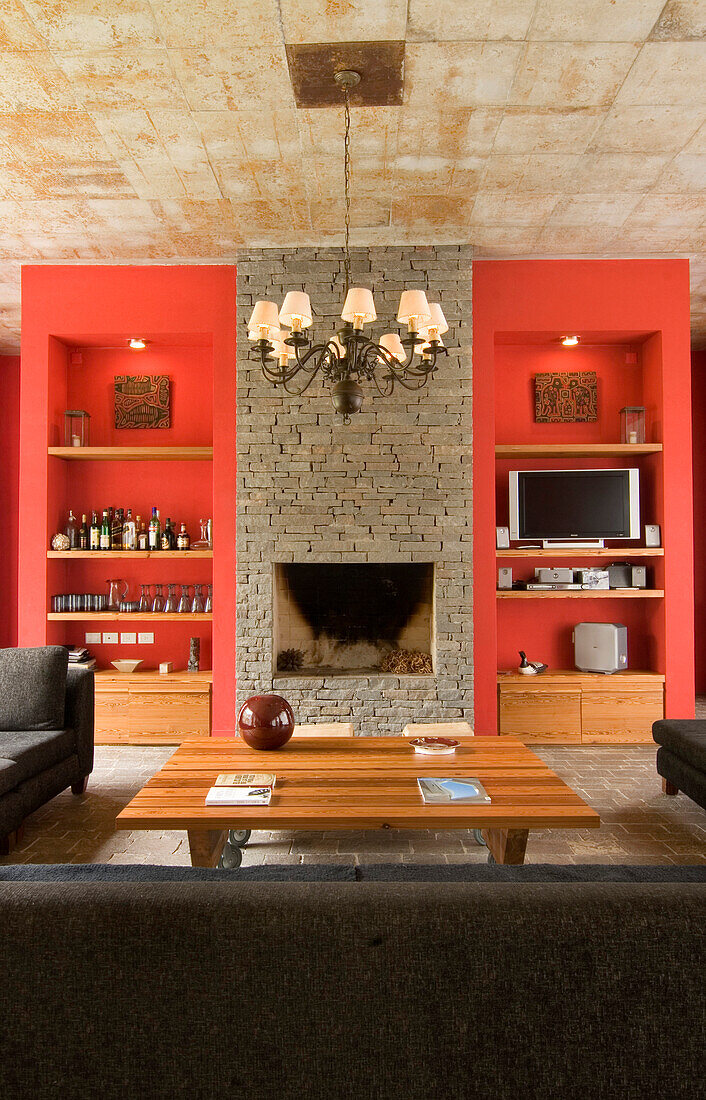 Exposed stone fireplace with recessed shelving and chandelier