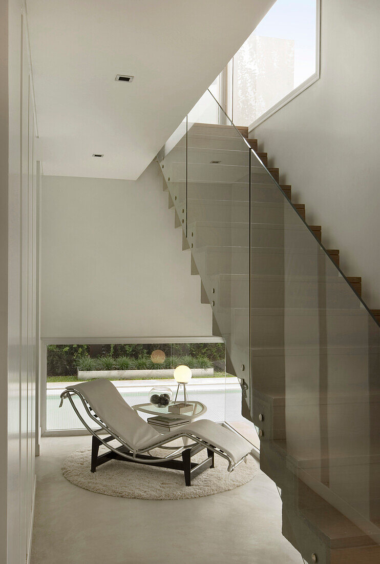 White leather recliner under stairway with glass divide