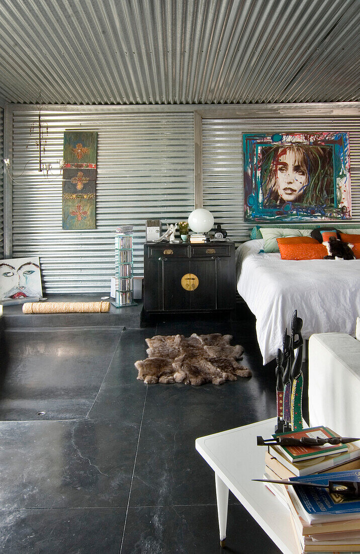 Schlafzimmer mit verzinktem Metall und chinesischem Nachttisch und Boden mit eingelassener Badewanne