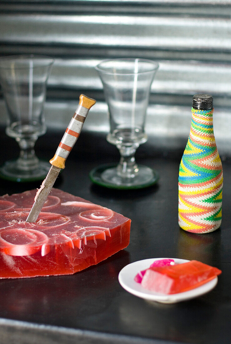 Antikes Messer mit Erdbeerseife und eine Flasche, die mit verschiedenfarbigen elektrischen Schnüren bedeckt ist