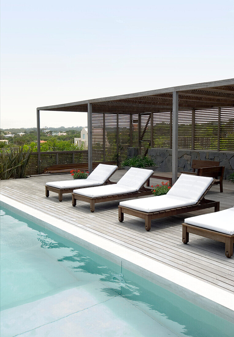 Sunloungers with pergola on poolside decking