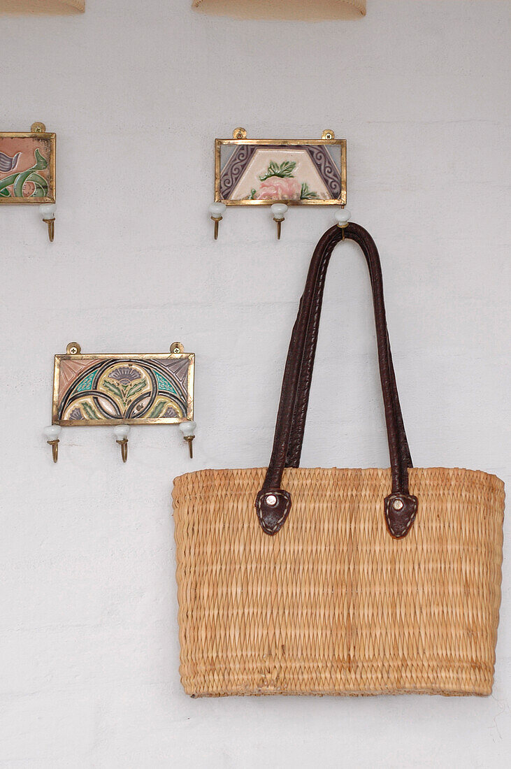 Einkaufstasche aus Weidengeflecht hängt an einem dekorativen Kleiderhaken