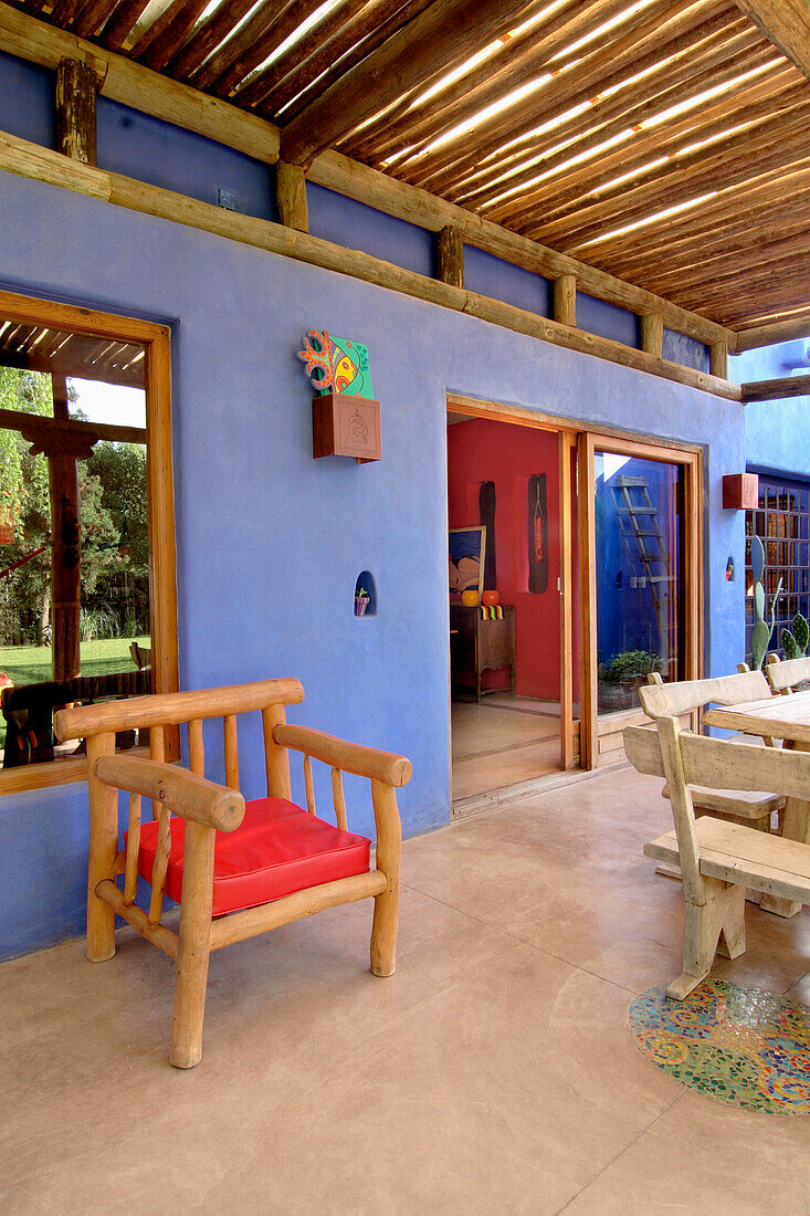 Eichentisch und Sitzbank mit Kaktus am Eingang zur blau gestrichenen Veranda