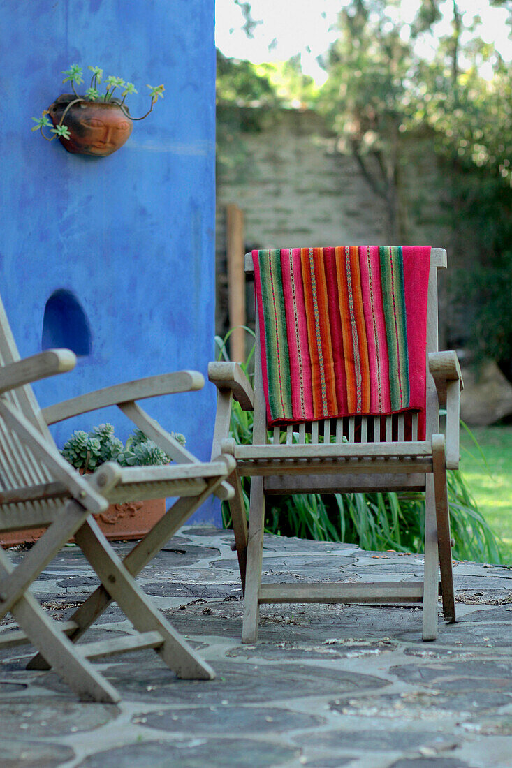 Wood chairs on patio terrace with Mexican blanket