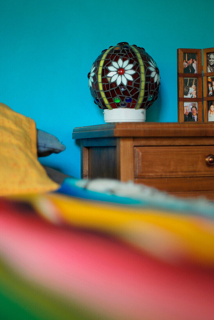 Nachtlampe aus Buntglas auf Kommode in türkisfarbenem Schlafzimmer