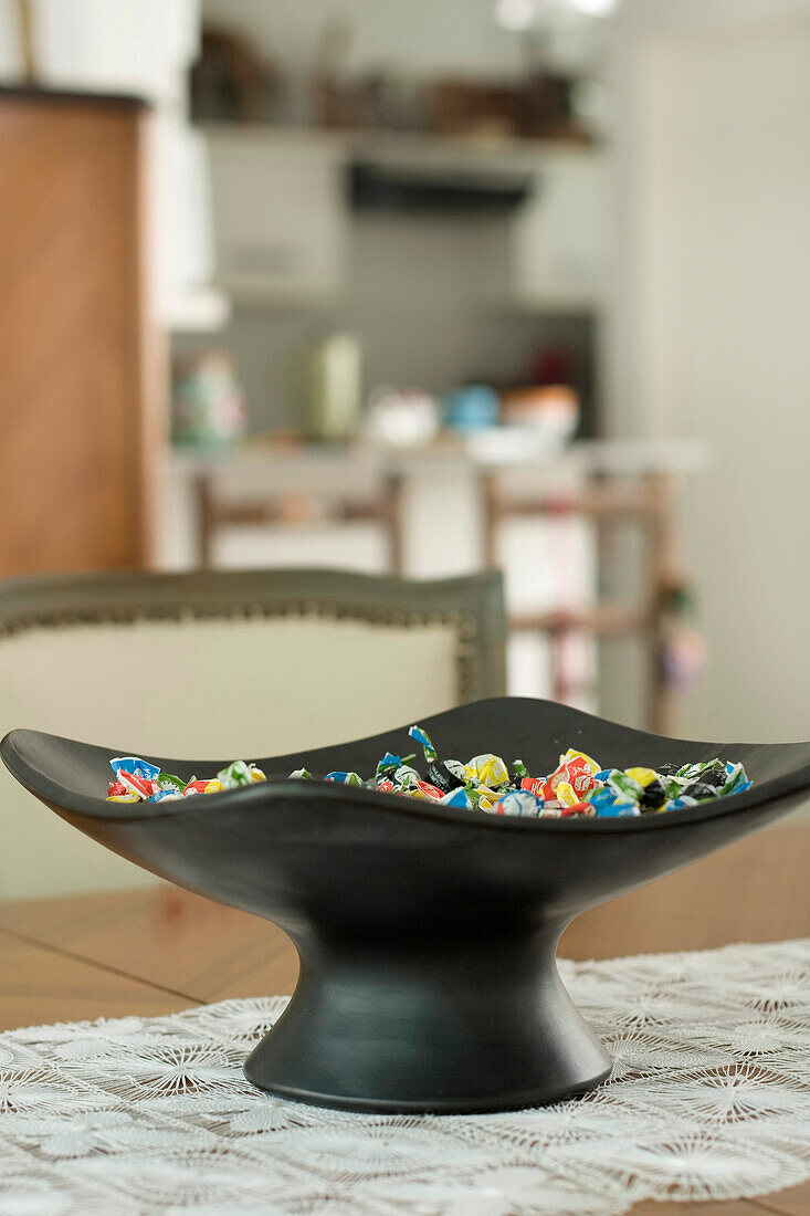 Black bowl on lace table runner filled with confectionary