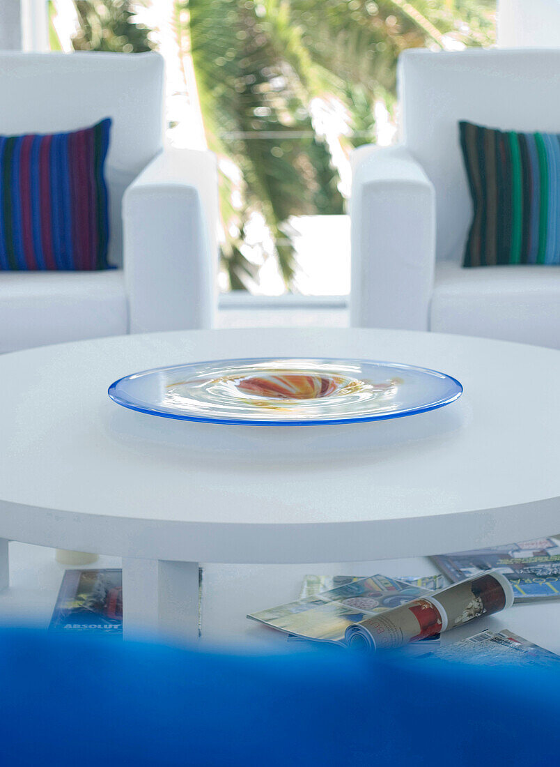 Weißes Wohnzimmer mit passenden Sesseln und handgefertigter Glasschale auf dem Tisch