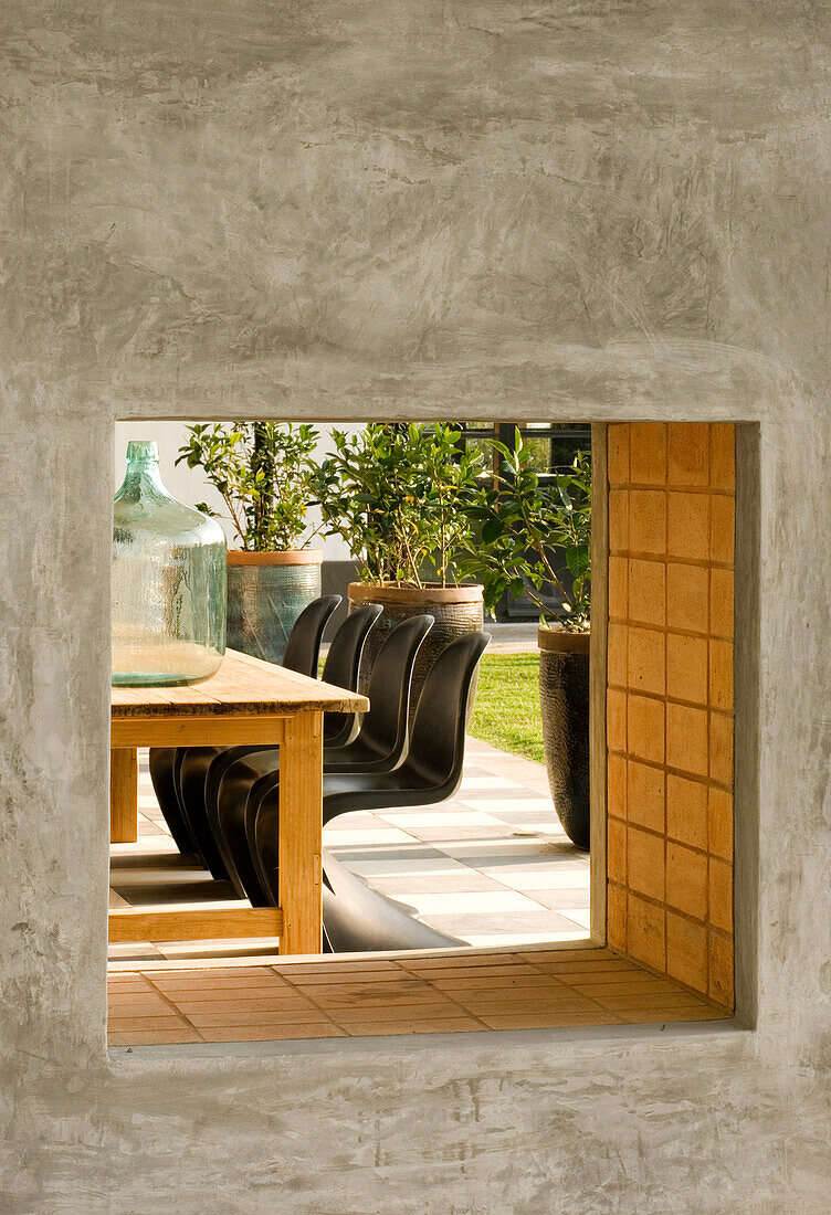 Wooden table with water container on outdoor veranda viewed through grill