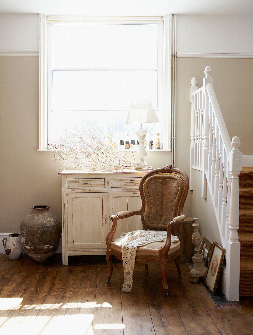 Antique chair under sunlit window in wood floored entrance hall