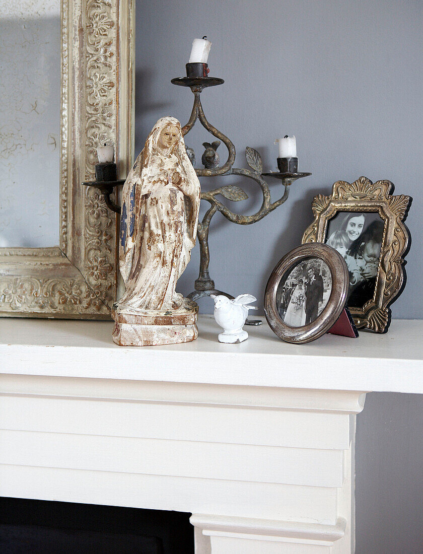 Figurine und silberne Bilderrahmen auf einem Kaminsims mit geschnitztem Spiegel und Kerzenständer