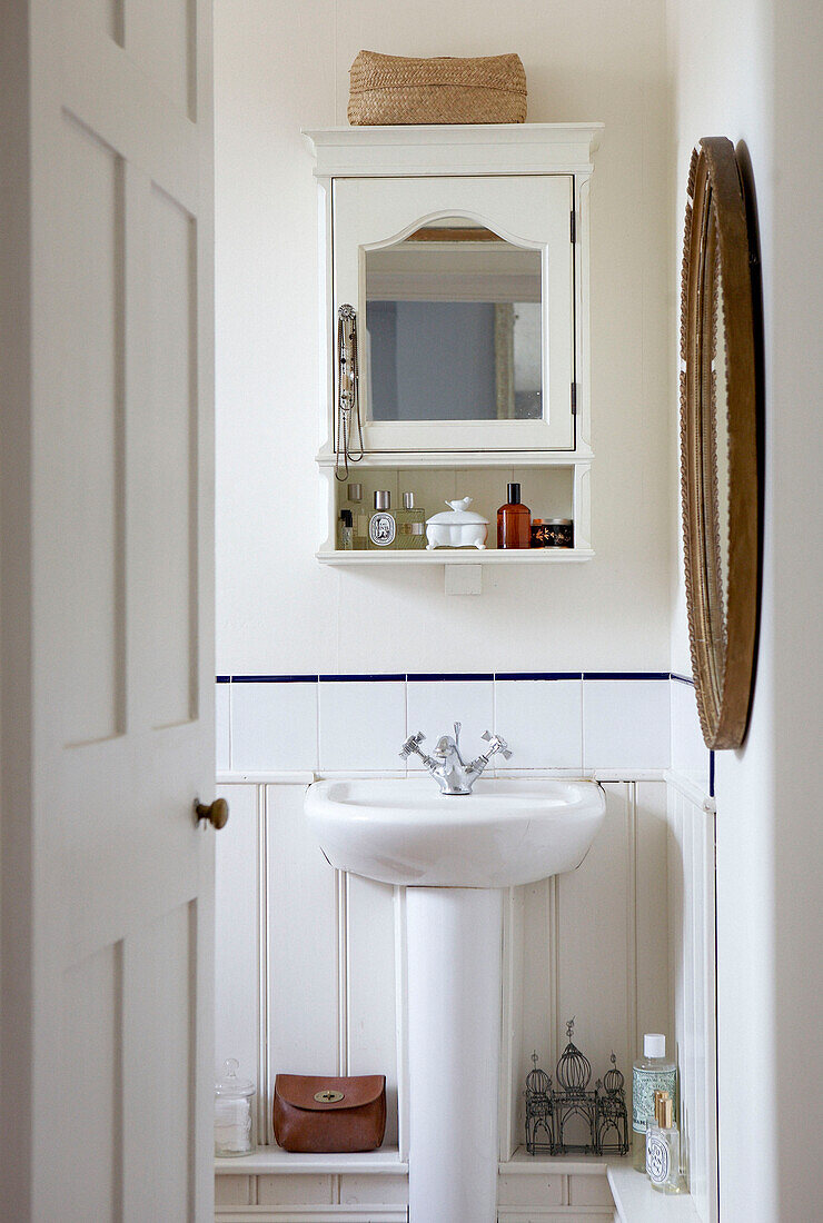 Spiegelschrank über dem Waschbecken in einem weiß getäfelten Badezimmer