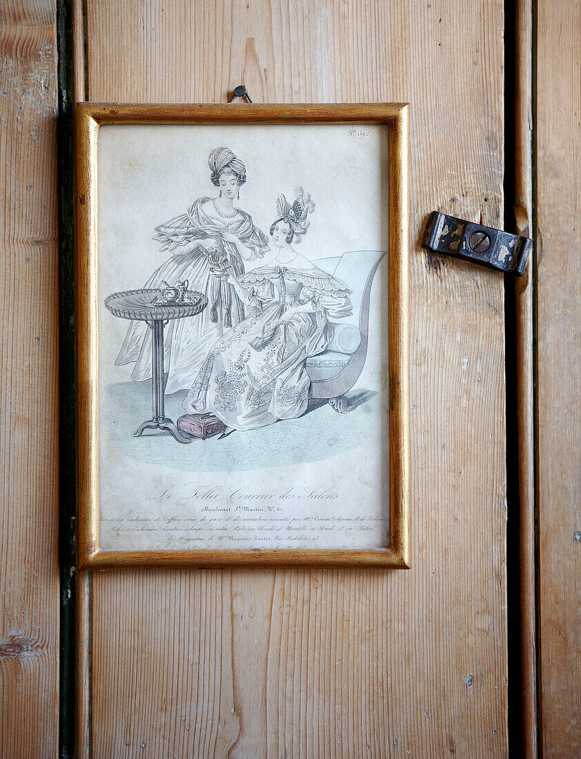 Black and white framed sketch hangs on wooden door with latch