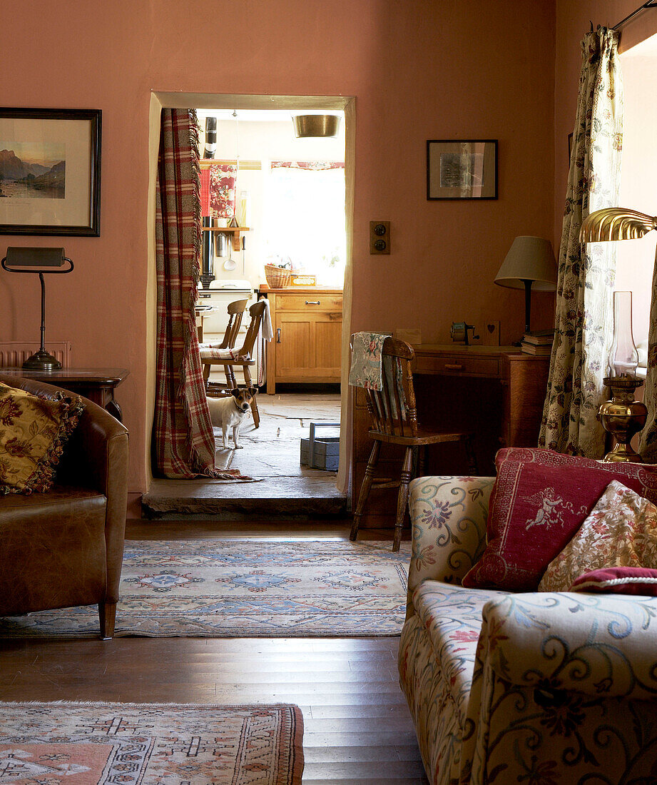 Gemusterte Teppiche auf dem Holzboden eines Wohnzimmers mit Blick durch die Vorhangtür zur Küche