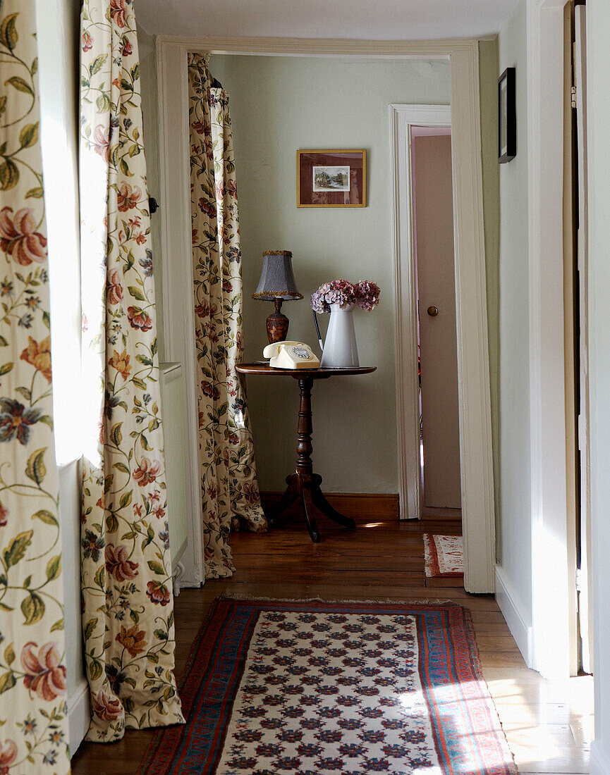 Patterned rug in hallway with floral curtains