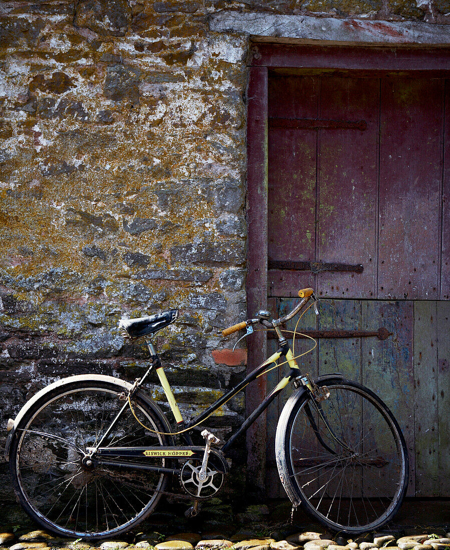 Fahrrad lehnt an Wand neben Stalltür
