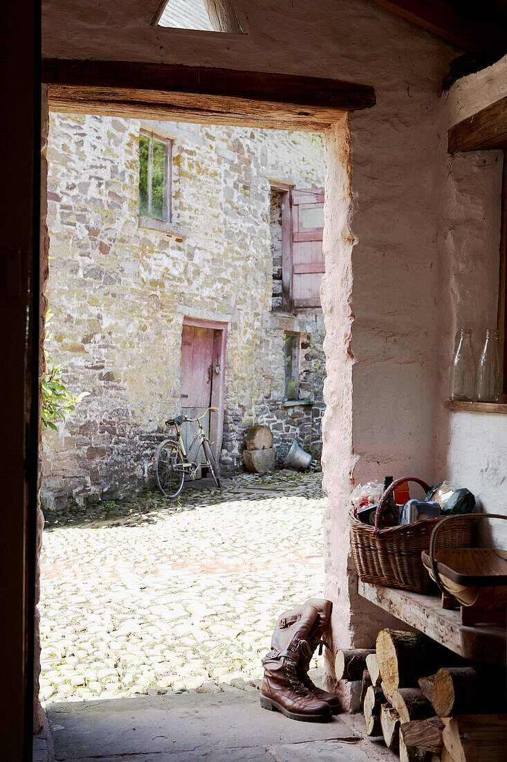 Blick durch die Tür zu einem Bauernhof mit Kopfsteinpflaster und einer Scheune