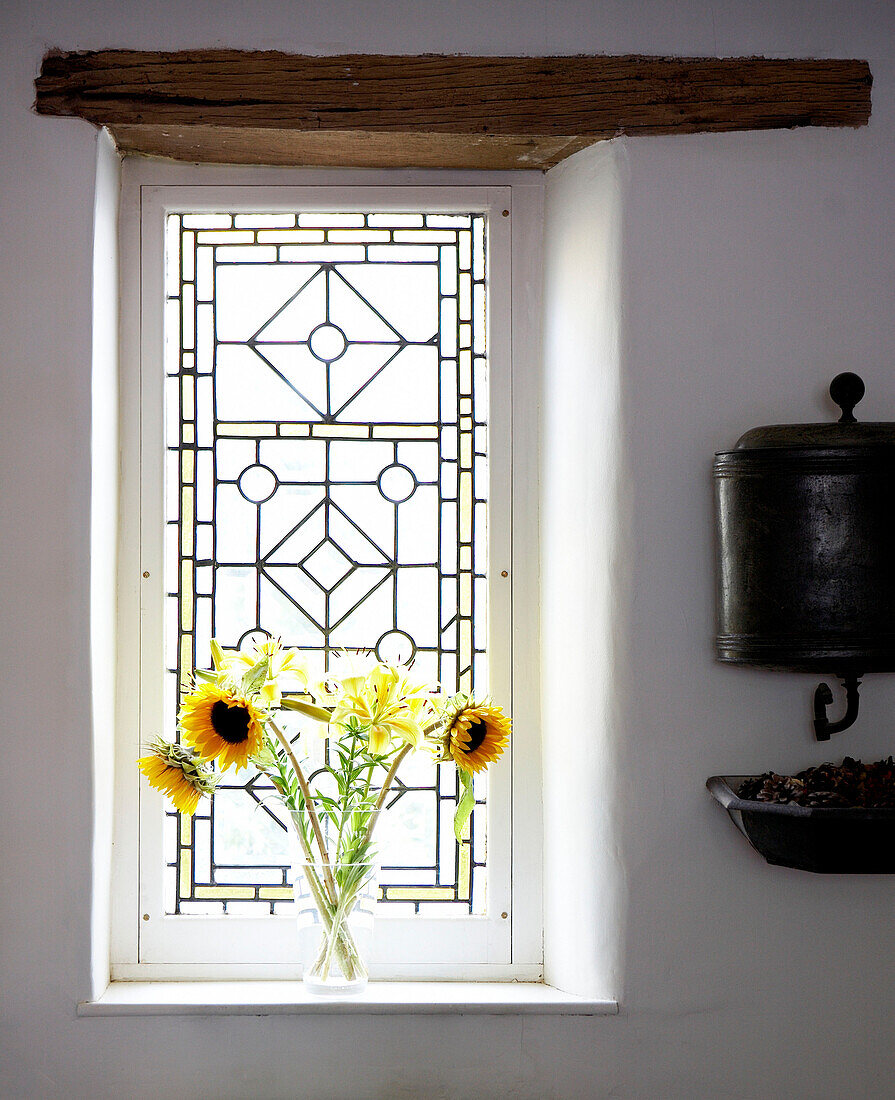 Vase mit Sonnenblumen auf sonnenbeschienener Fensterbank mit Originalbalken