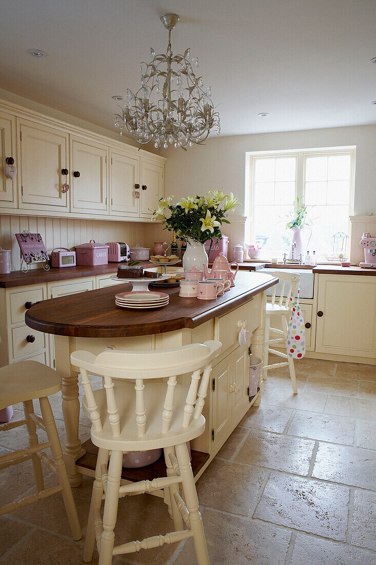 Helle Küche mit rosafarbenen Geräten und Holzinsel mit weiß lackierten Barhockern