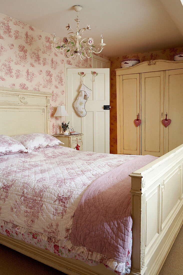 Rosa geblümte Steppdecke und lackierte Schlafzimmermöbel