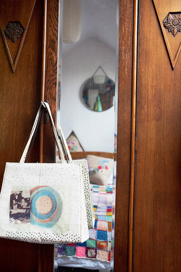 Retro handbag hangs on door of wooden wardrobe
