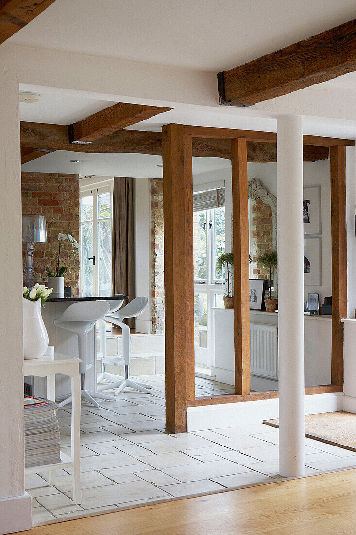 Blick auf die Küche vom Flur aus, mit weißen Bodenfliesen, offenen Balkenwänden und freiliegenden Ziegeln
