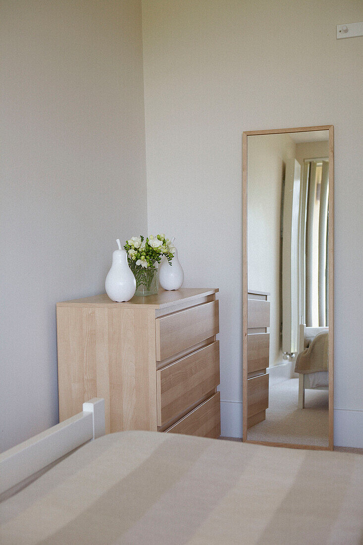 Spiegel in voller Länge und passende Kommode im Schlafzimmer mit cremefarbenem Bettbezug