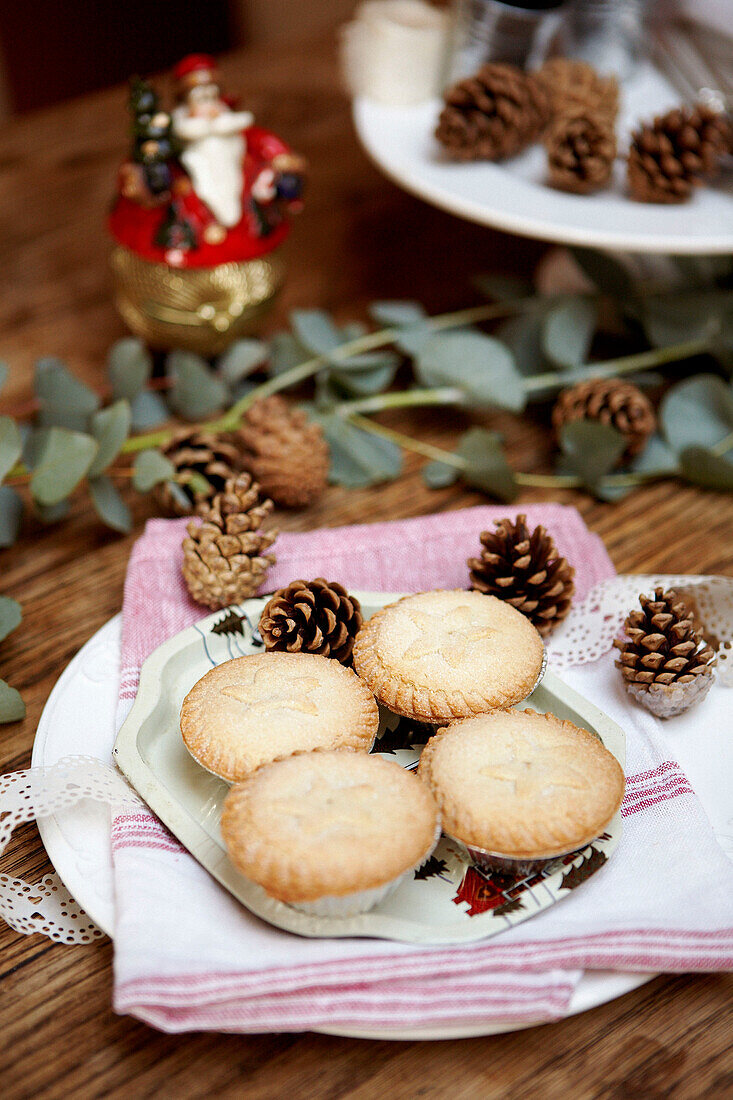 Mince pies and pine cones on plate with napkin