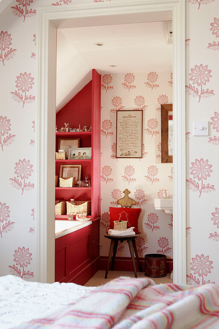View through doorway with floral patterned wallpaper to bathroom with red accent colour