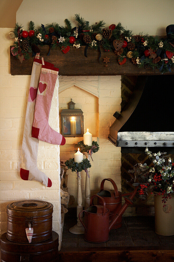 Christmas stockings hang on fireside with lit candles