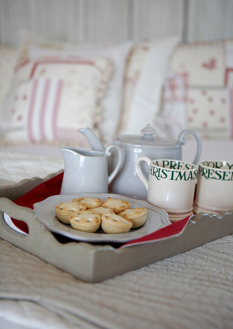 Teekanne und Milchkännchen mit Tassen und Mince Pies auf einem Küchentablett