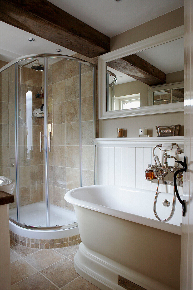Shower cubicle with sliding door in corner of cream tied bathroom in farmhouse conversion